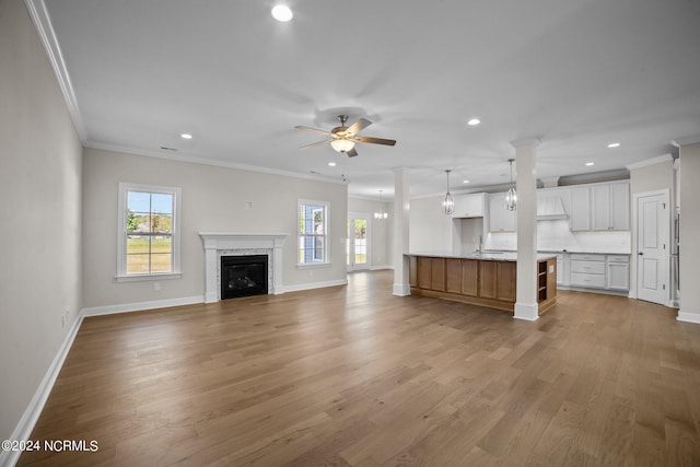 unfurnished living room featuring ornamental molding, plenty of natural light, recessed lighting, baseboards, and wood finished floors