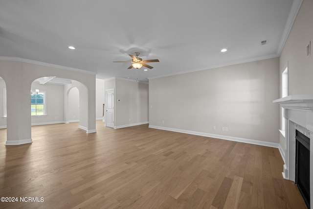 unfurnished living room featuring arched walkways, ceiling fan, a fireplace, light wood finished floors, and recessed lighting