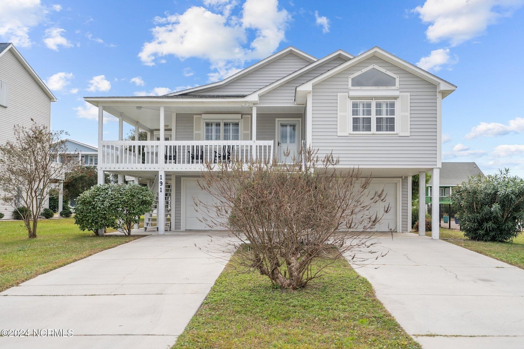 view of front of home featuring a front yard, covered porch, and a garage