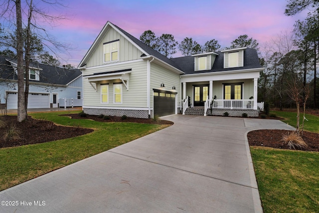 view of front of house with a garage, covered porch, and a lawn