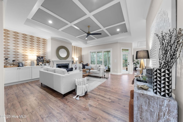 living room with coffered ceiling, ceiling fan, a fireplace, and wood-type flooring