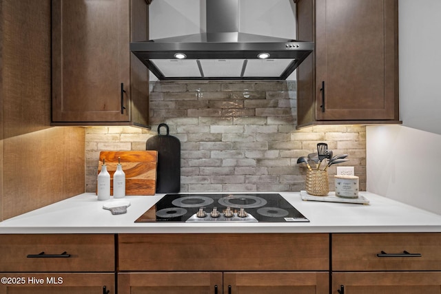 kitchen featuring black electric cooktop, decorative backsplash, and exhaust hood