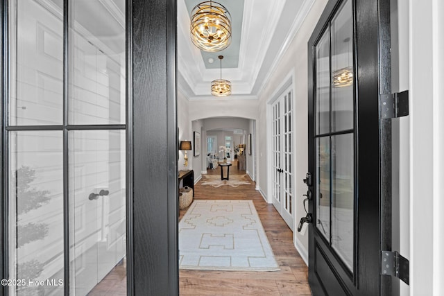 entrance foyer featuring hardwood / wood-style flooring, ornamental molding, a raised ceiling, and french doors