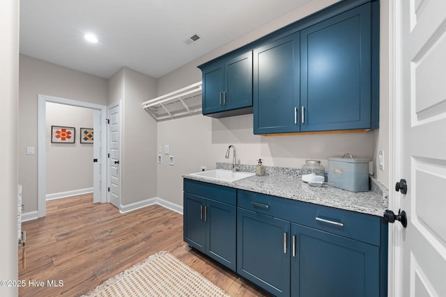 laundry area featuring washer hookup, sink, hardwood / wood-style floors, and cabinets