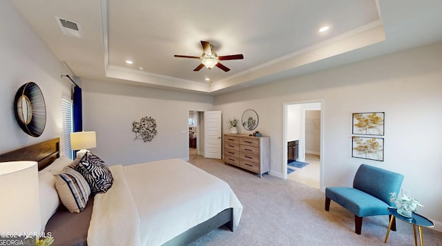 bedroom with connected bathroom, ceiling fan, light colored carpet, and a raised ceiling