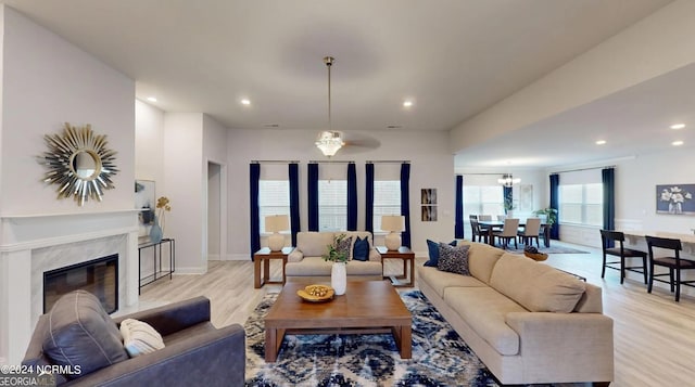 living room featuring ceiling fan, a fireplace, and light wood-type flooring