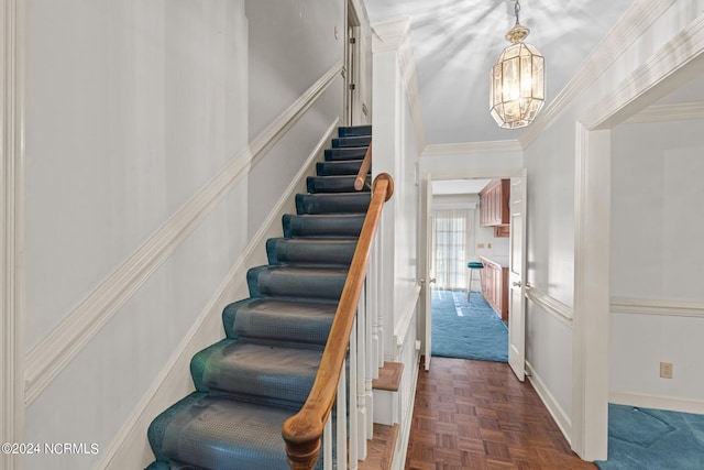 stairway featuring parquet flooring, ornamental molding, and a notable chandelier