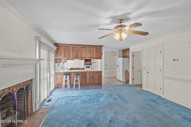 kitchen featuring light colored carpet, white appliances, kitchen peninsula, and ornamental molding