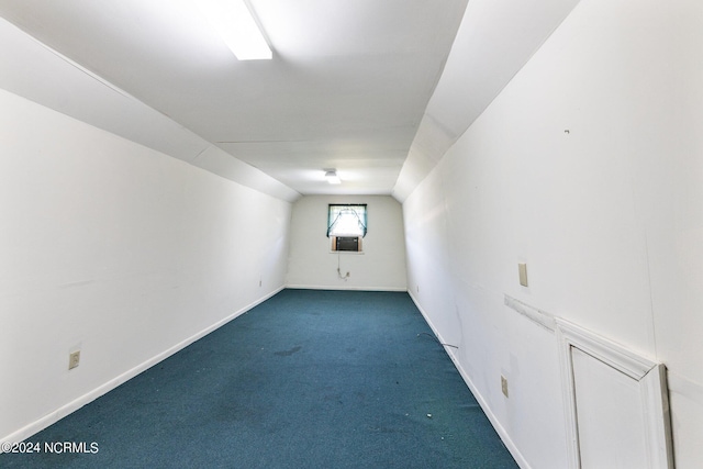 additional living space with dark colored carpet and vaulted ceiling