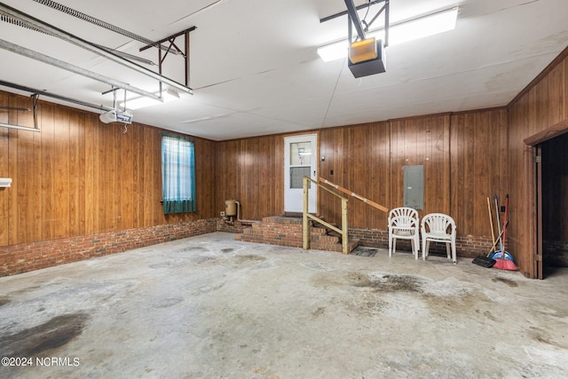 garage featuring electric panel, wood walls, and a garage door opener