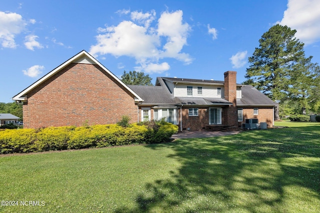 rear view of house featuring central air condition unit and a lawn