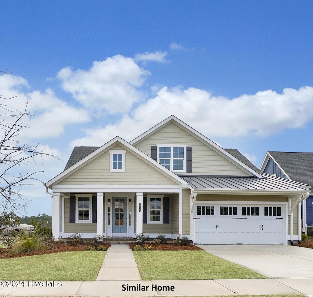 view of front of property featuring a front yard, a garage, and covered porch