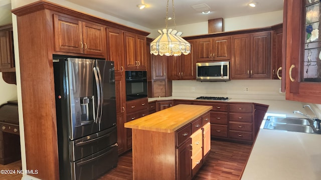 kitchen featuring a kitchen island, stainless steel appliances, dark hardwood / wood-style floors, wooden counters, and sink