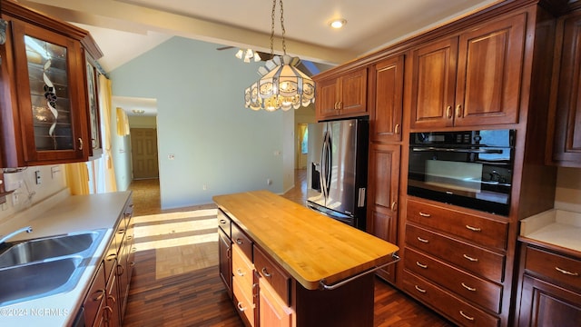 kitchen with stainless steel fridge, butcher block countertops, a kitchen island, sink, and black oven