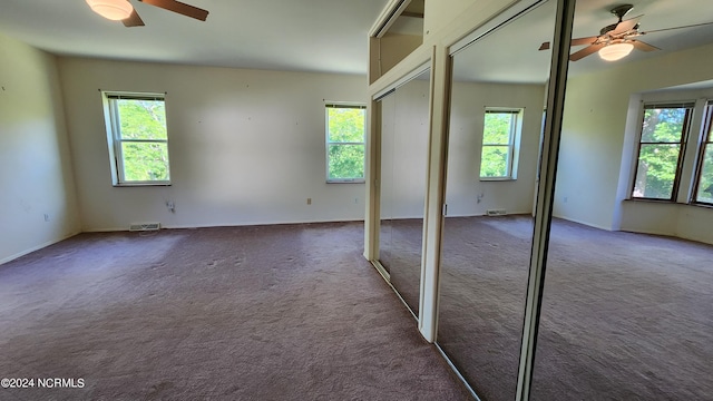 unfurnished bedroom with ceiling fan and dark carpet