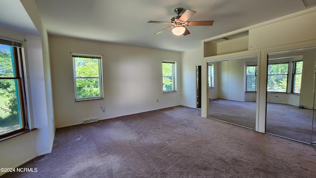 unfurnished bedroom featuring ceiling fan, multiple windows, and carpet floors