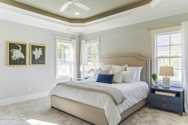 carpeted bedroom with crown molding, ceiling fan, and a tray ceiling