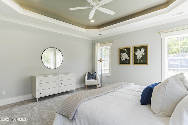 carpeted bedroom featuring ceiling fan, a raised ceiling, and multiple windows