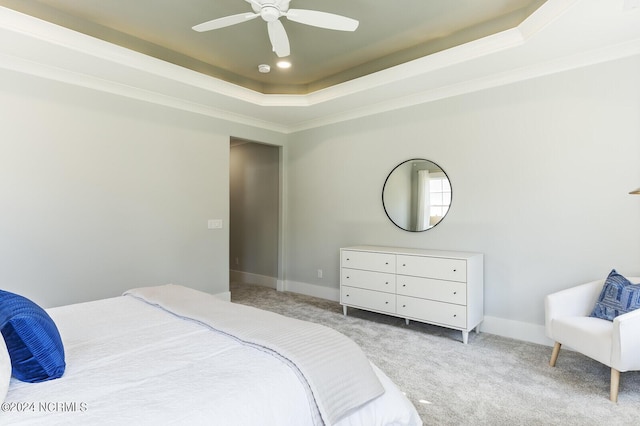 carpeted bedroom with a raised ceiling, ornamental molding, and ceiling fan