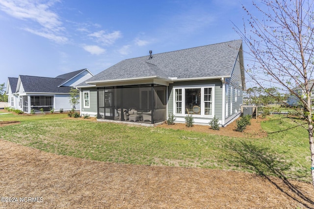 rear view of house featuring a sunroom, a yard, and roof with shingles