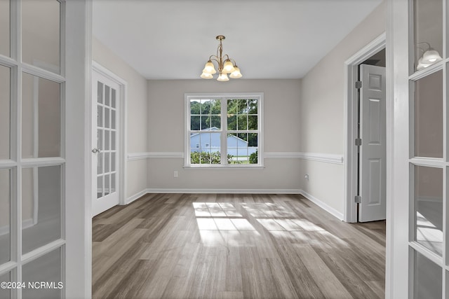 unfurnished dining area with hardwood / wood-style floors and a chandelier