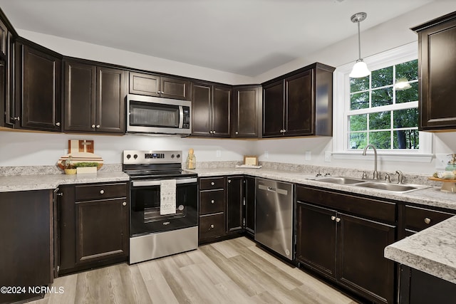 kitchen with dark brown cabinetry, sink, light hardwood / wood-style flooring, appliances with stainless steel finishes, and pendant lighting