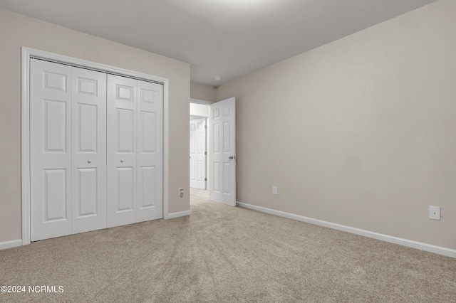 unfurnished bedroom featuring light carpet and a closet