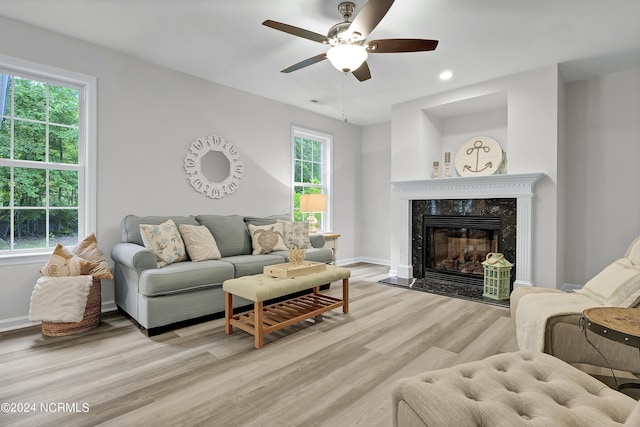 living room featuring light hardwood / wood-style flooring, a fireplace, and ceiling fan