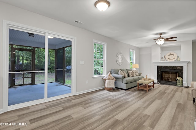 living room featuring ceiling fan, a fireplace, and light hardwood / wood-style floors