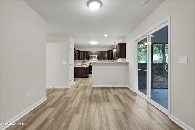 kitchen with stainless steel appliances, dark brown cabinetry, and light hardwood / wood-style floors