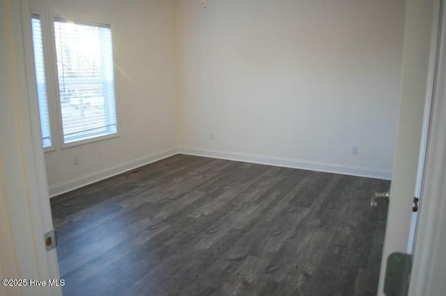 spare room featuring dark hardwood / wood-style floors and plenty of natural light