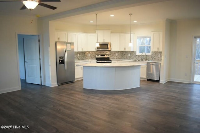 kitchen featuring dark hardwood / wood-style flooring, stainless steel appliances, pendant lighting, white cabinets, and a center island