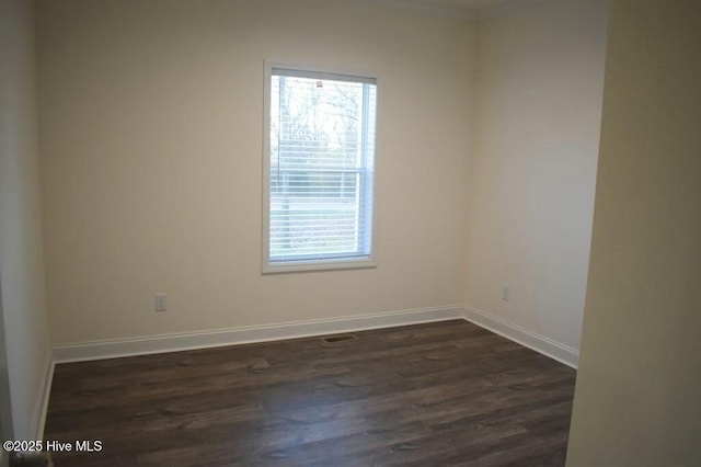 empty room with dark hardwood / wood-style flooring and plenty of natural light