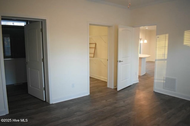 unfurnished bedroom featuring dark hardwood / wood-style floors, a walk in closet, connected bathroom, and a closet