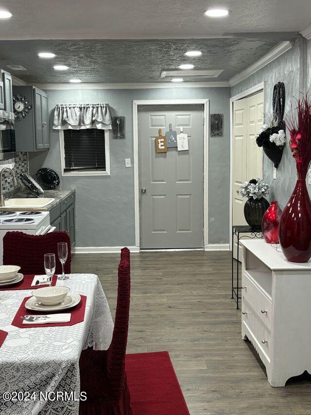 interior space with dark hardwood / wood-style floors, crown molding, and sink