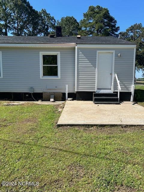 back of house with entry steps and a lawn