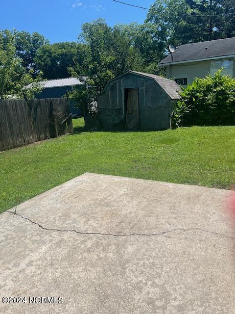 view of patio / terrace with an outbuilding, fence, and a storage shed