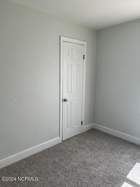 unfurnished room featuring carpet and baseboards