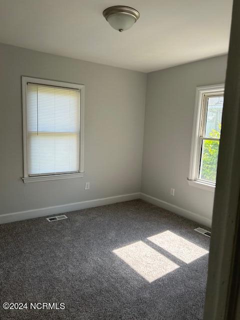 empty room featuring carpet, visible vents, and baseboards