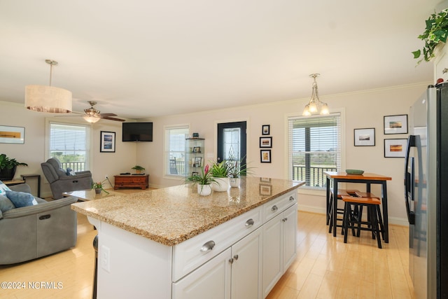 kitchen featuring stainless steel fridge, light hardwood / wood-style flooring, white cabinetry, hanging light fixtures, and a kitchen island