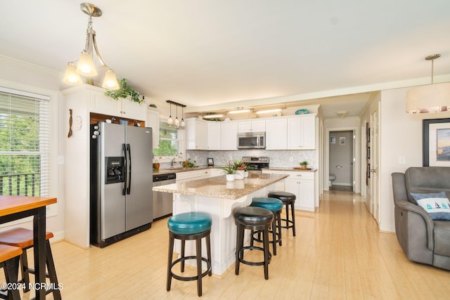 kitchen with white cabinetry, pendant lighting, stainless steel appliances, and a kitchen island