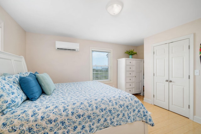 bedroom featuring an AC wall unit, light hardwood / wood-style floors, and a closet