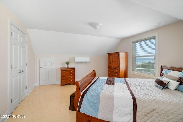 bedroom with lofted ceiling, a wall mounted AC, and light hardwood / wood-style flooring