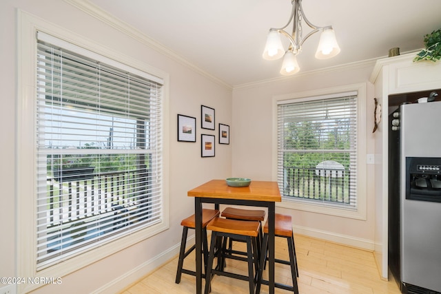 dining room featuring ornamental molding, a healthy amount of sunlight, an inviting chandelier, and light wood-type flooring