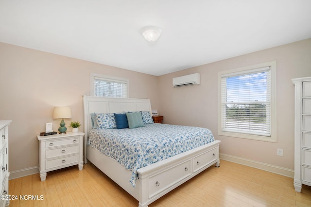 bedroom with light wood-type flooring and an AC wall unit