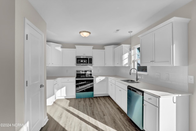 kitchen featuring sink, white cabinetry, stainless steel appliances, pendant lighting, and light hardwood / wood-style flooring