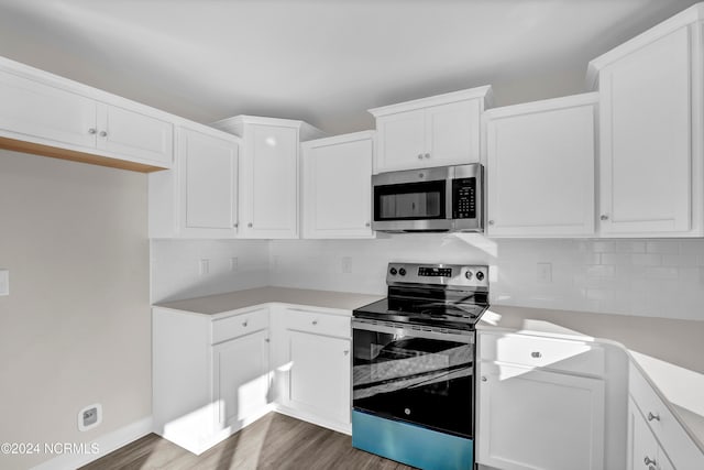 kitchen with white cabinetry, dark hardwood / wood-style floors, appliances with stainless steel finishes, and decorative backsplash