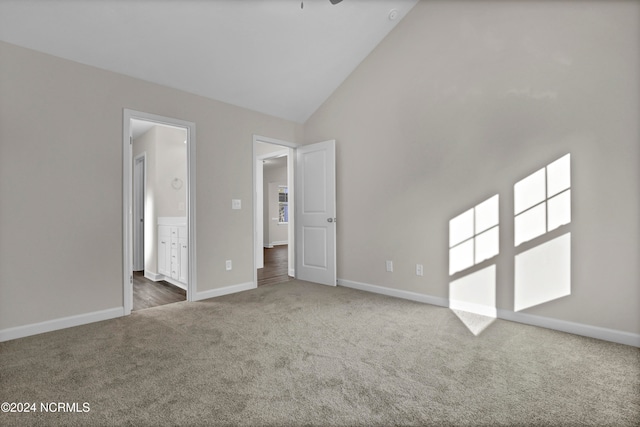 carpeted spare room featuring high vaulted ceiling and ceiling fan