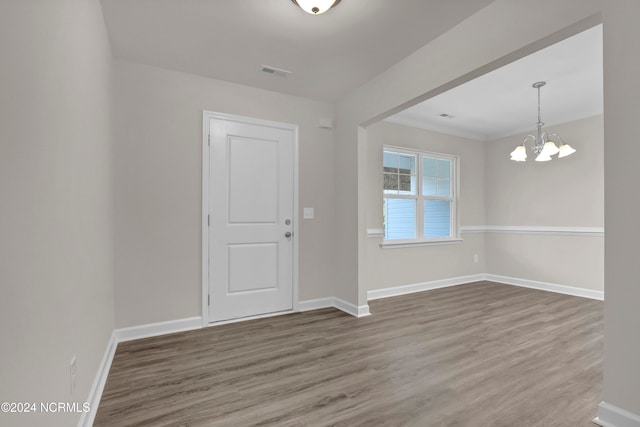 spare room featuring crown molding, hardwood / wood-style flooring, and a notable chandelier