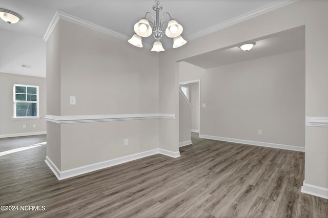 spare room with dark wood-type flooring, ornamental molding, and a chandelier